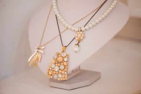 Luxury gold jewelry on set holders and in jewelry box on light dressing table and wardrobe shelves